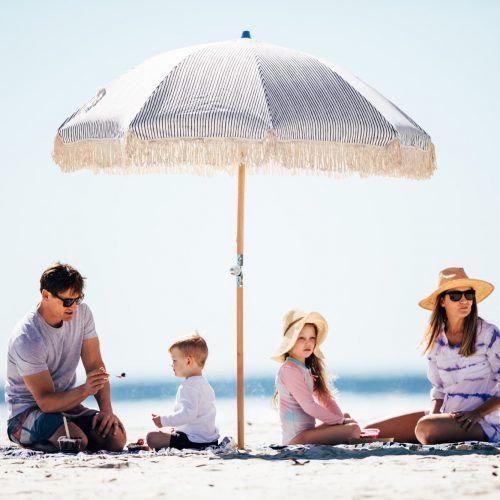 gc-tourism-burleigh-currumbin-family-on-rug-under-umbrella-on-beach